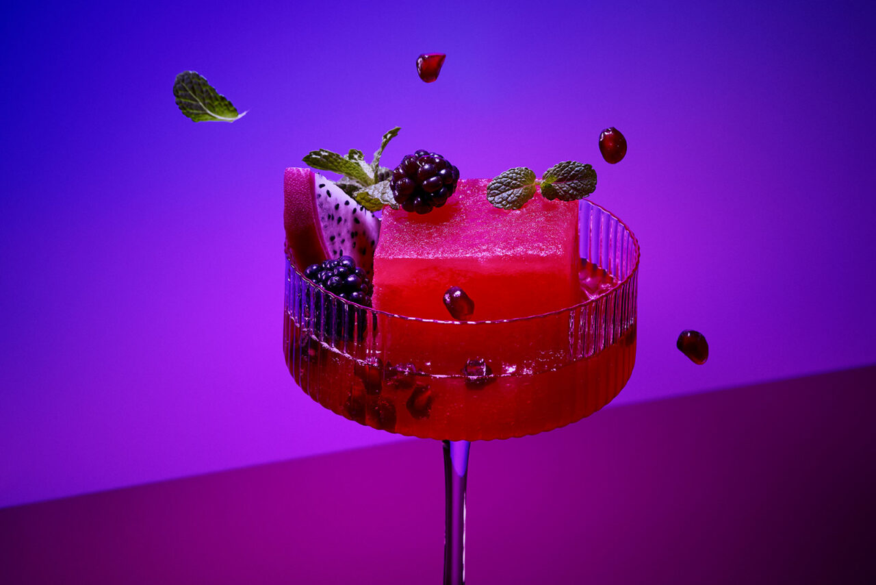 cocktail with big ice cube and garnich bold colorful food photography